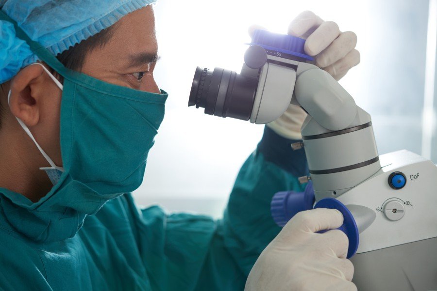 Surgeon examining a medical procedure through a surgical microscope