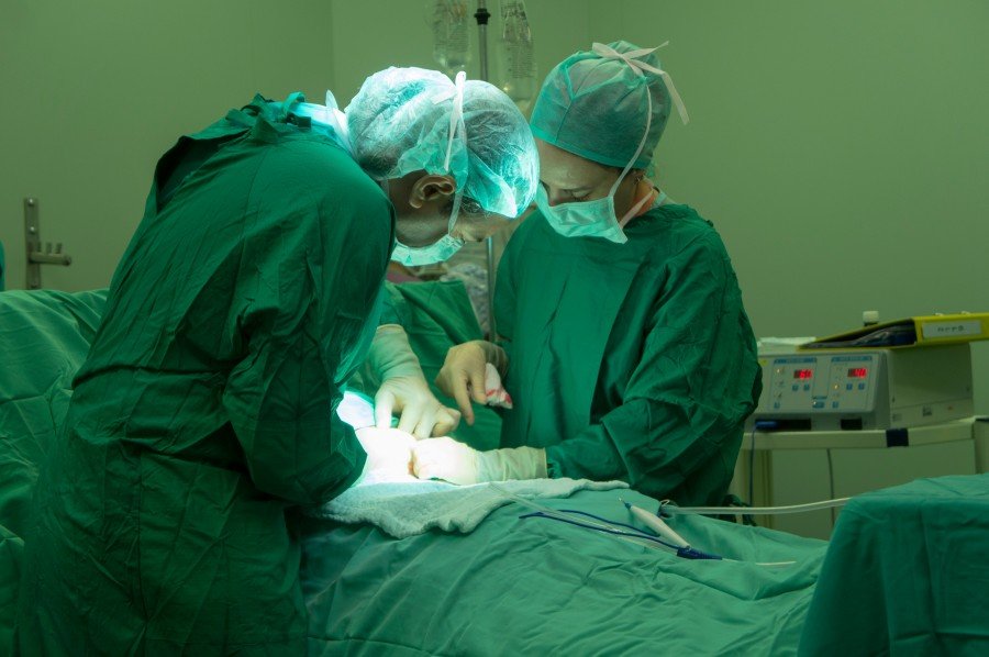 Surgeons in protective gowns, masks, and caps performing an operation in a hospital operating room